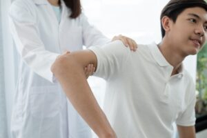 Homem na consulta com medica analisando lesão no ombro