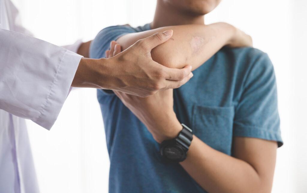 Homem sendo avaliado por médico por uma possível lesão no cotovelo