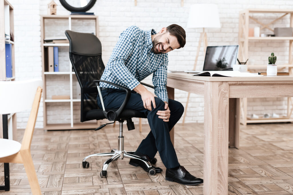 Homem com a mão sobre o joelho com possível dor.